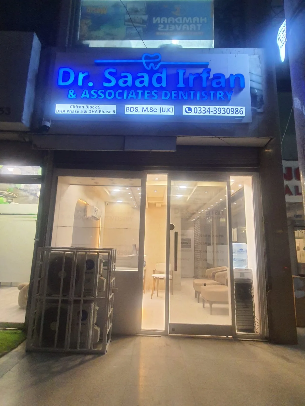 The Clifton Block 9 shopfront lit at night, with the clinic sign and the Clifton direct line above the entrance